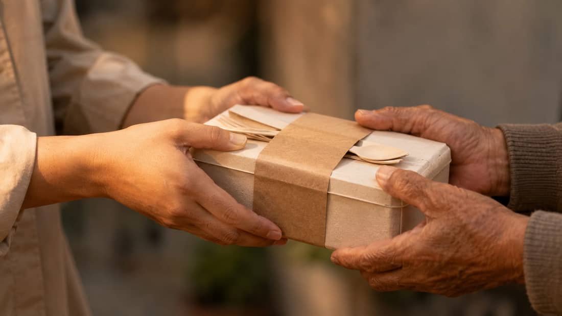Hands passing a care package, representing Al Ranim Cares community work